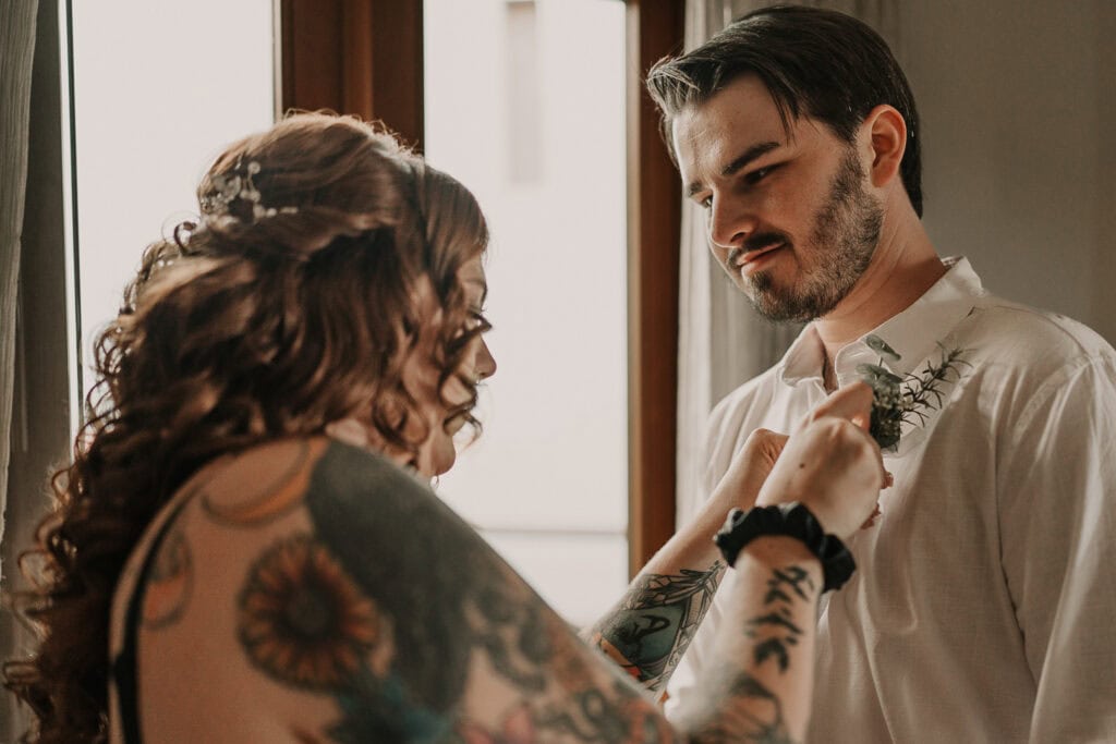 Marissa pins David's boutonniere on his shirt.