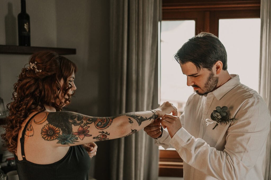 A groom helps the bride put her bracelet on before their wedding.