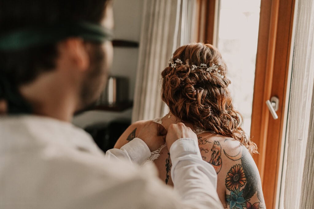 David wears a blindfold while he buttons Marissa's wedding gown.