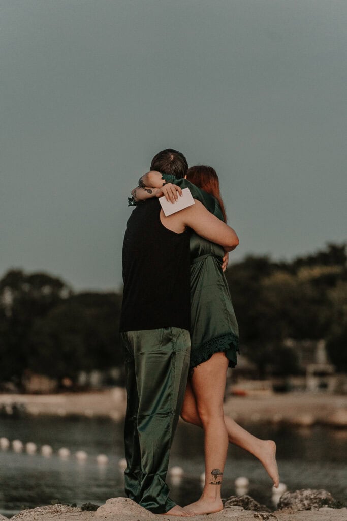 Marissa and David hug while standing on the beach at sunrise.