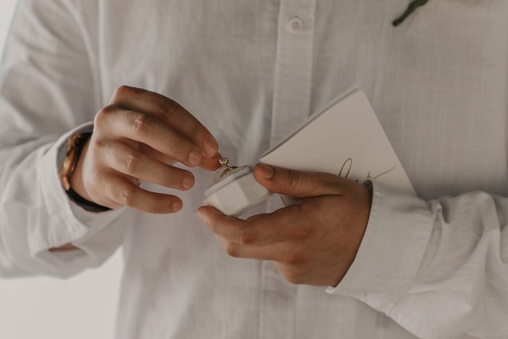 The groom pulls the bride's wedding ring out of a box.