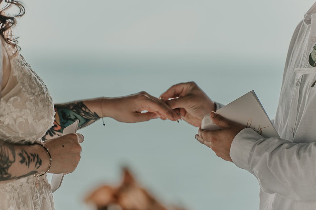 A closeup of the groom putting the ring on the bride's hand.