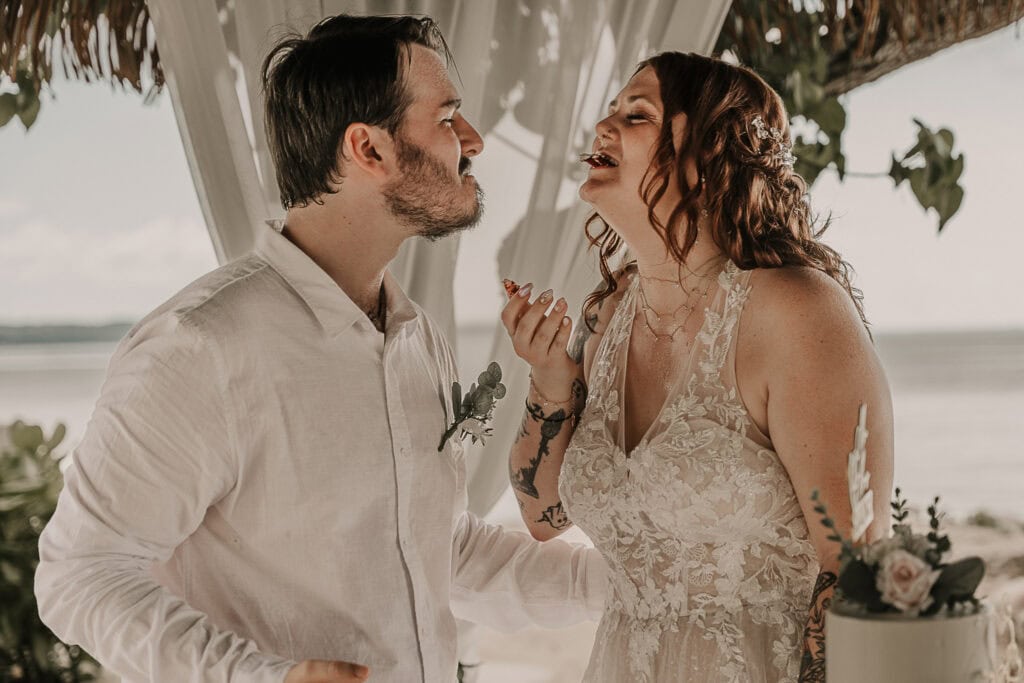 A couple feeds each other wedding cake.