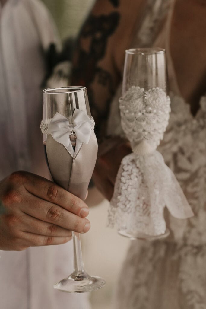 A closeup of lacy bride and groom champagne glasses.