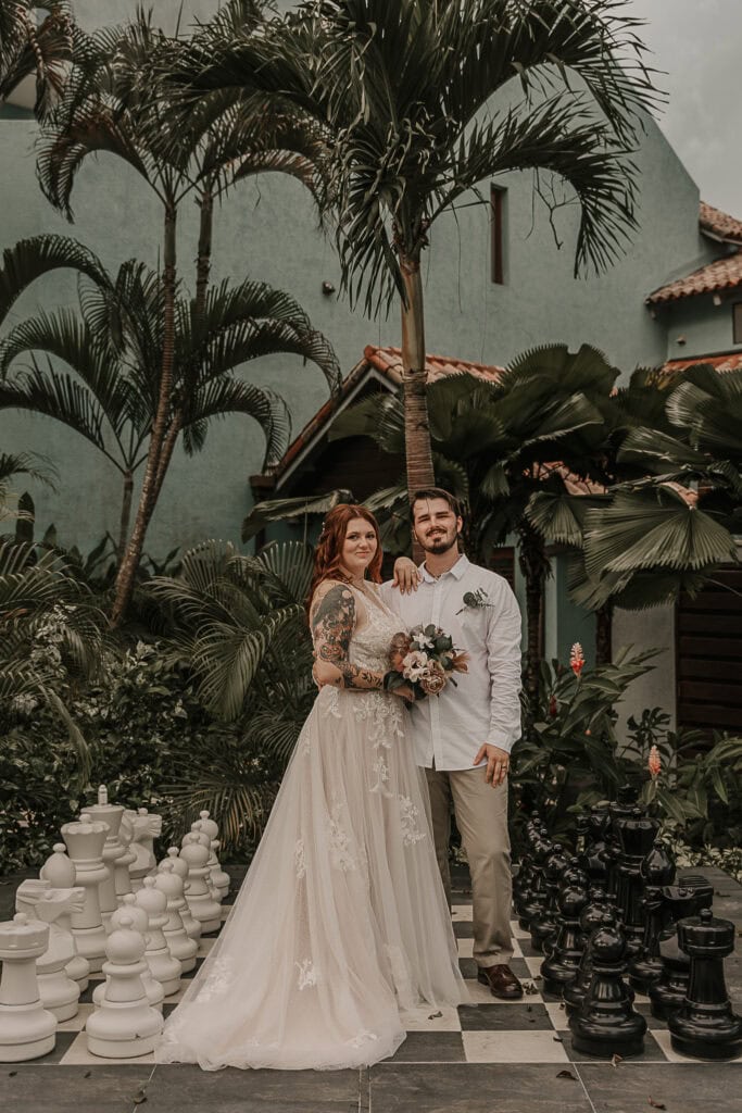 Marissa and David stand on a giant chess game in the garden at Sandals.