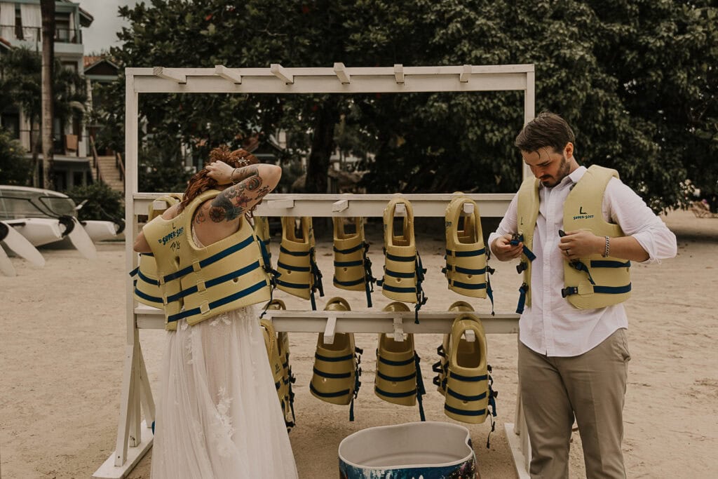 A couple puts life jackets on over their wedding attire.