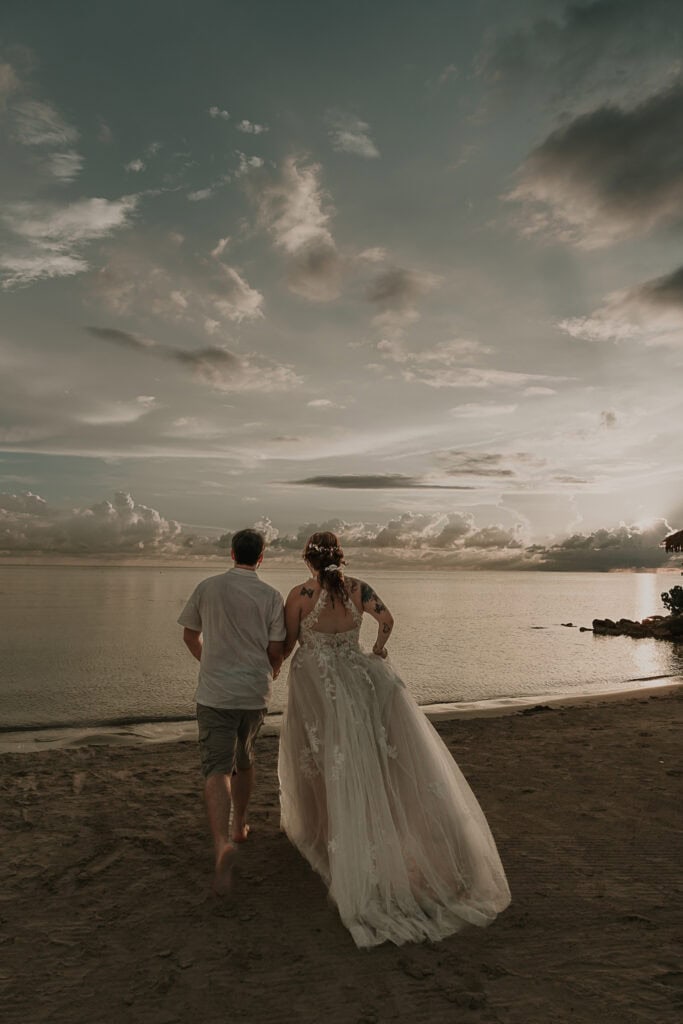 Marissa and David run towards the ocean in their wedding attire.