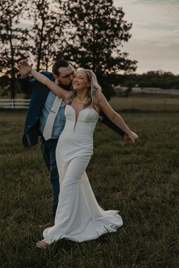 A couple dances in a field during their wedding celebration.