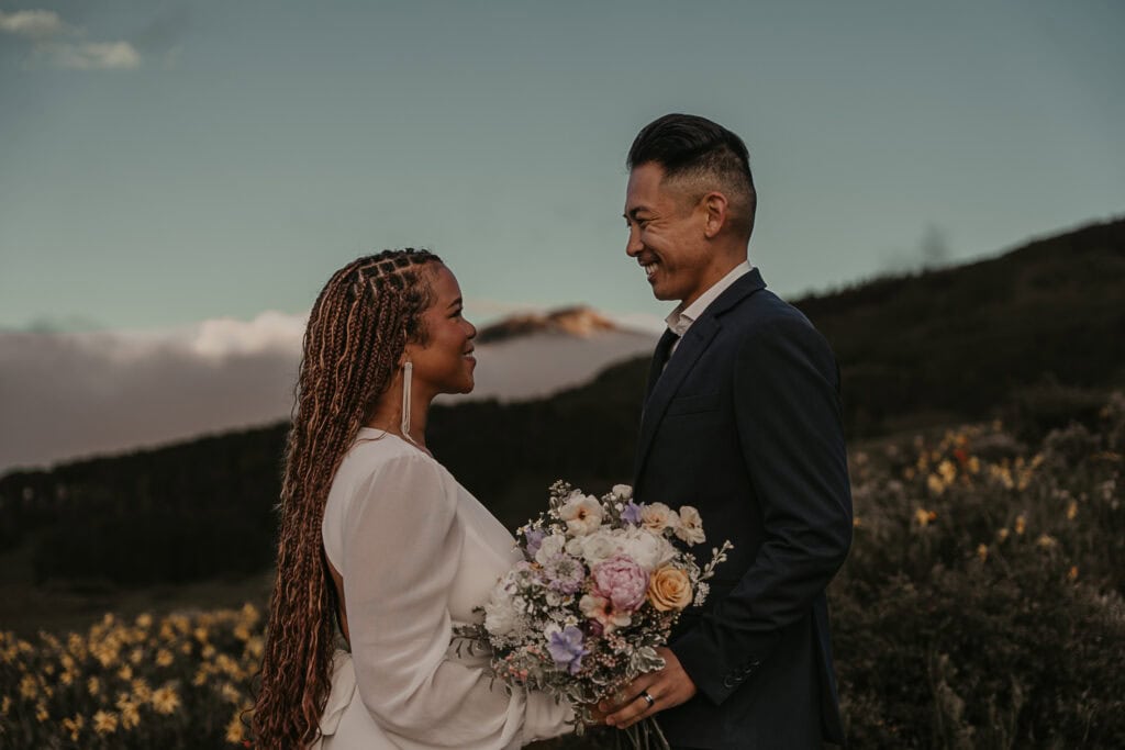 Marrisa and Janie stand facing each other with a mountain peak in between them in the distance.