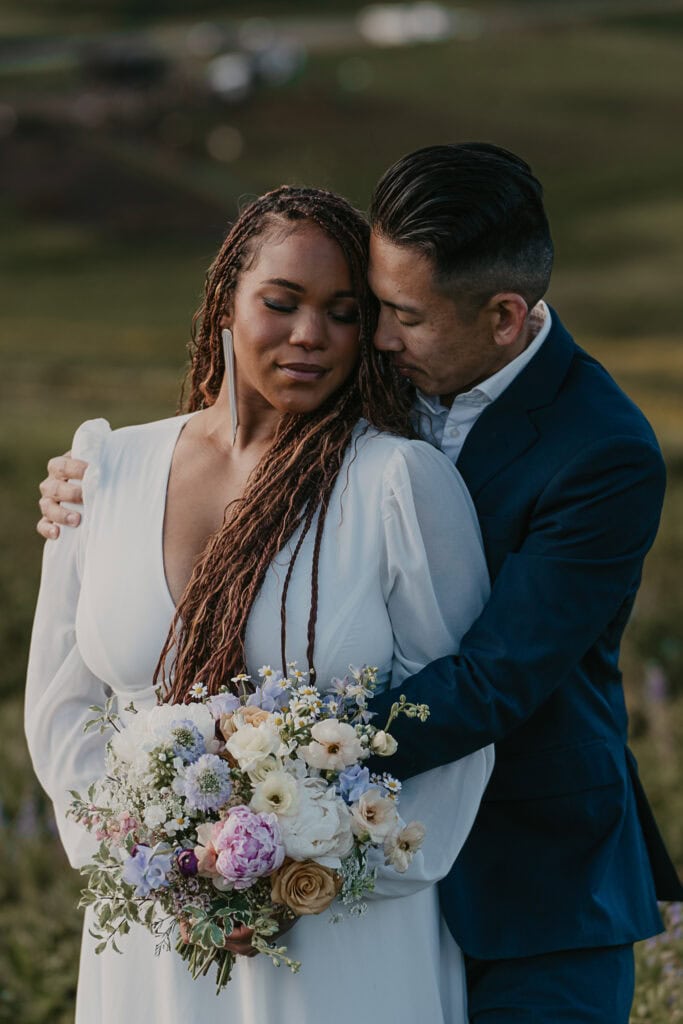 A bride and groom have their eyes closed, faces touching.