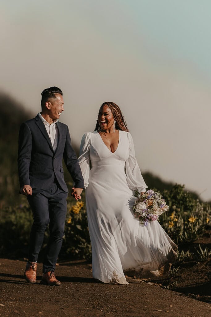 Marissa & Janiel look at each other laughing as they walk down a mountain in the fog.