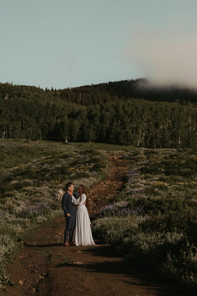 Marissa and Janiel enjoy a beautiful morning walk in their wedding attire. A foggy forest is behind them.