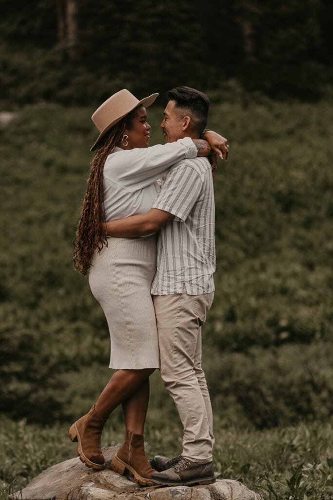 Marissa and Janiel stand on a rock while embracing.