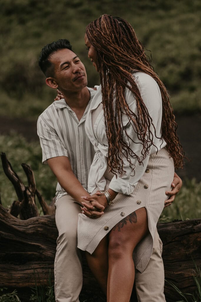 A couple looks fondly at each other while she sits on his lap.