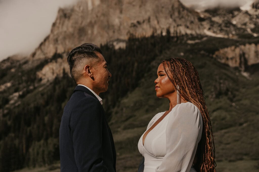 A couple says their vows in front of a mountain.