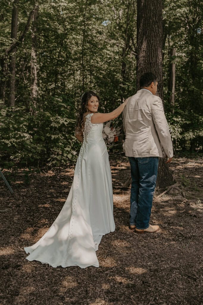 Anita has her hand on John's shoulder during their first look on their wedding day. He hasn't turned around yet.