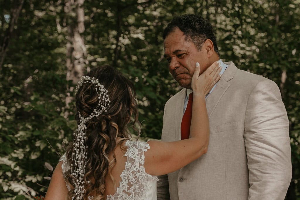 Anita places her hand tenderly on John's face as tears roll down his face from seeing her in her wedding gown for the first time.