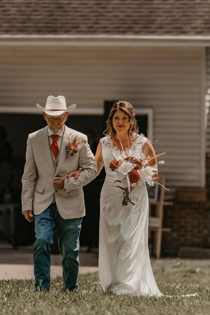 A dad walks his daughter down the aisle of her backyard wedding.