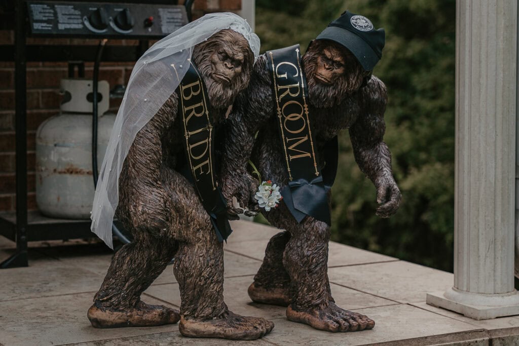 Sasquatch couple statue with bride and groom sashes, sets on a couples porch.