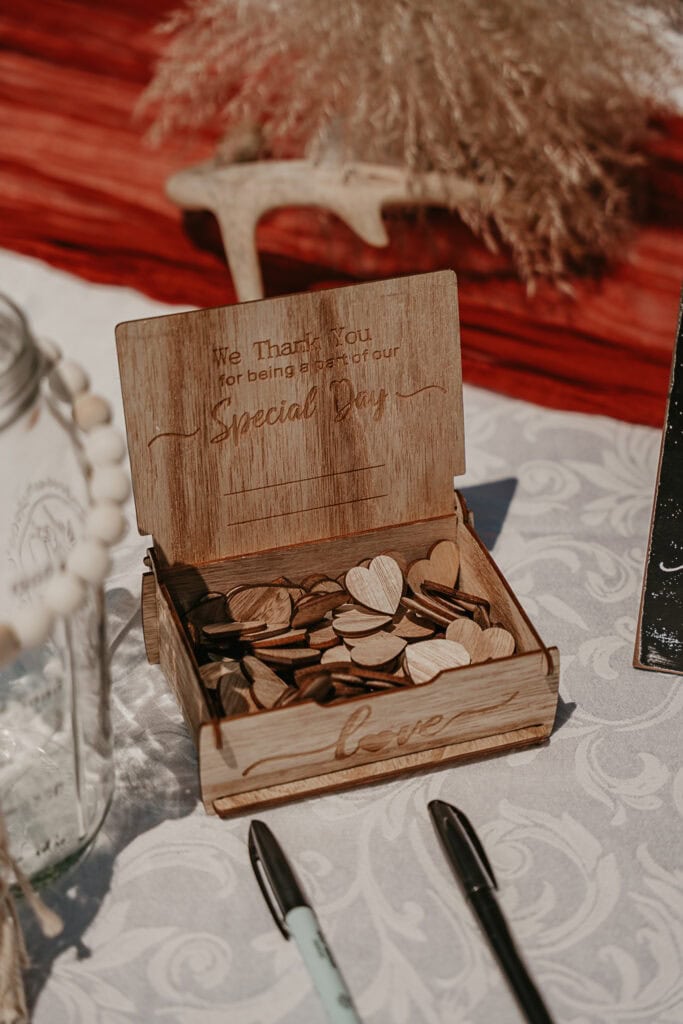 Wooden hearts for guests to sign and drop in a jar at a wedding.