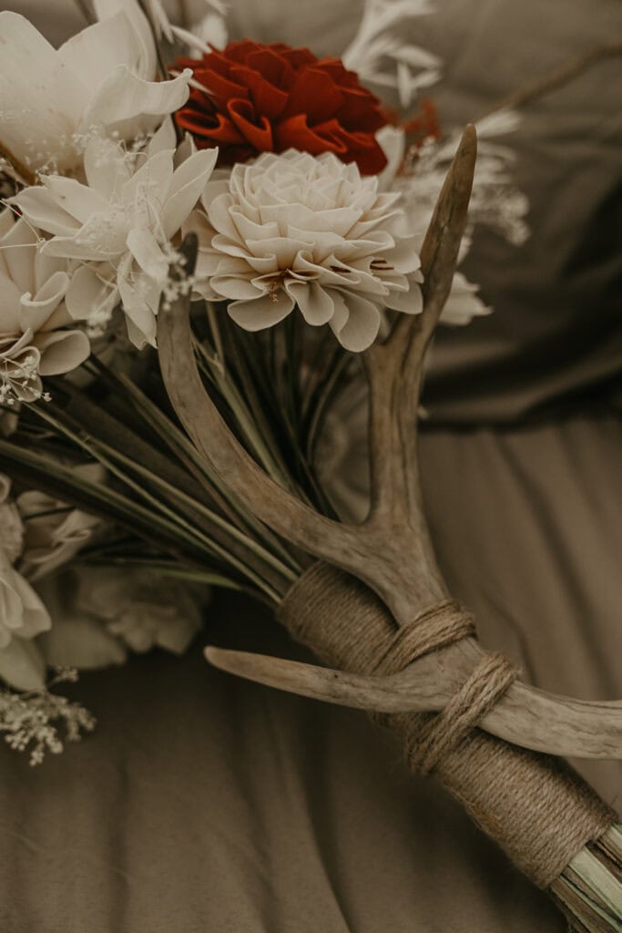 A bridal bouquet with a deer antler attached to the stem.