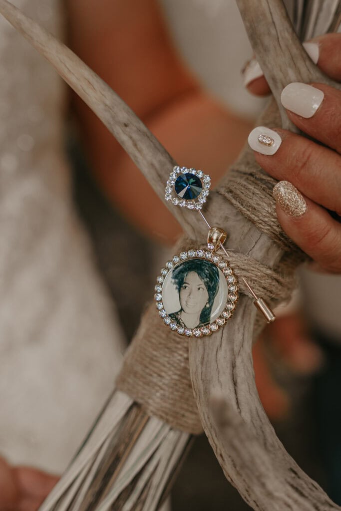 A locket with a photo of the bride's deceased mom is pinned to her bouquet with a blue stone.