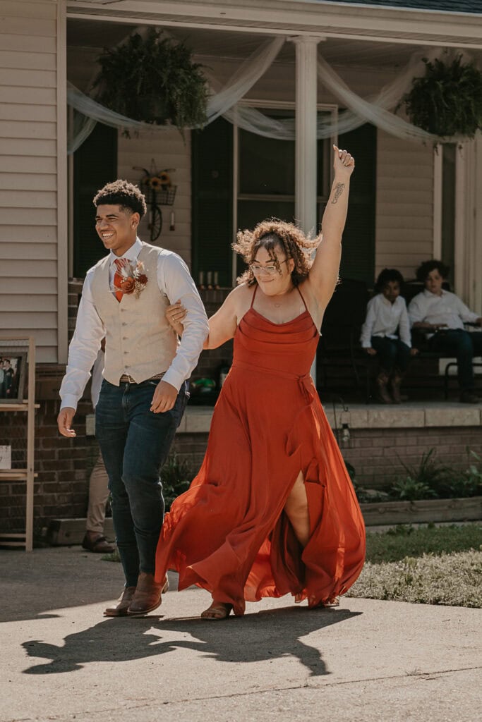 Bridesmaid throws her arm up, dancing with a groomsman.