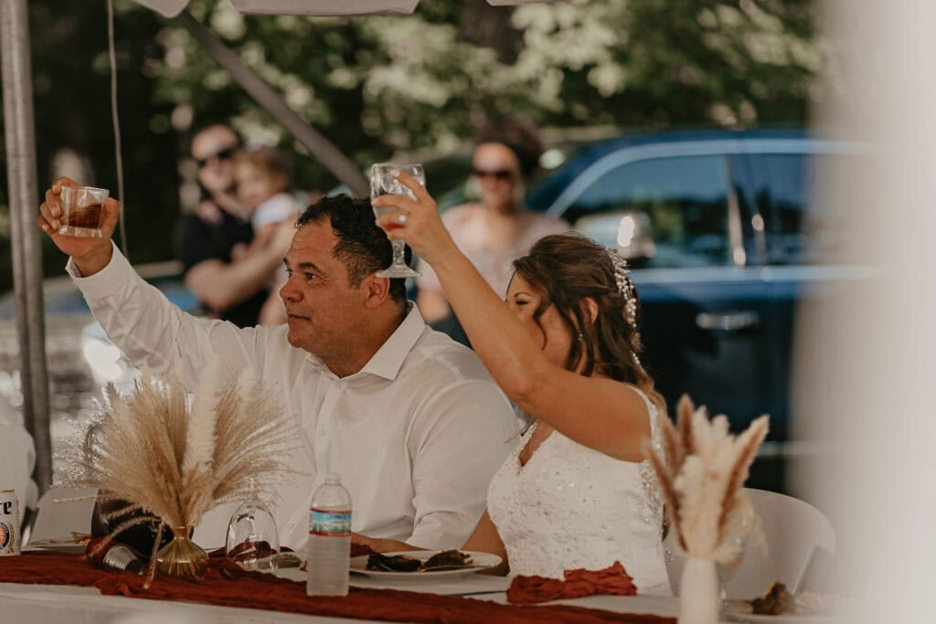 Anita and John raise their glasses in a toast at their outdoor wedding.