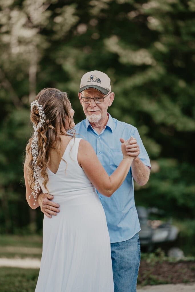 The bride dances with her dad during her wedding reception outside.