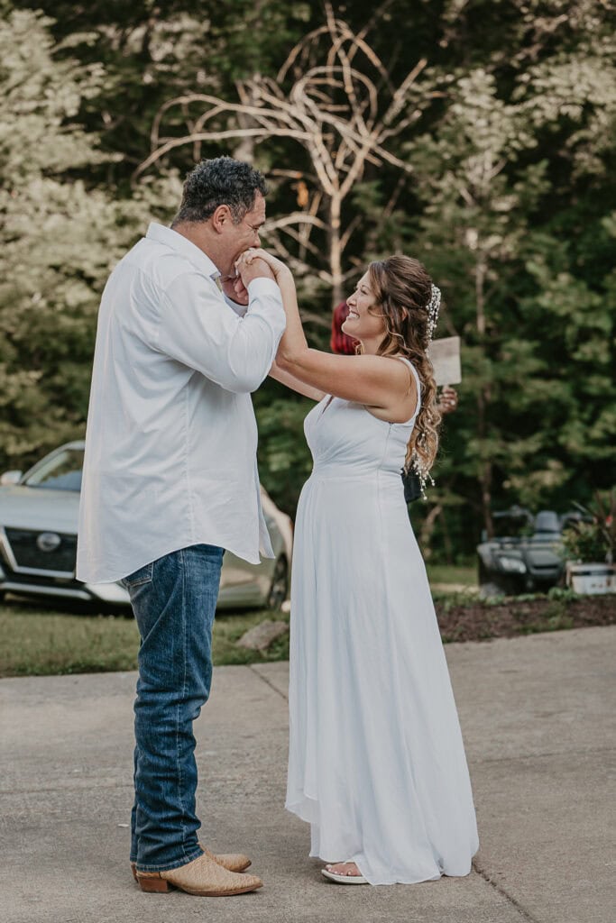 Groom kisses the bride's hands during their dance at their reception.