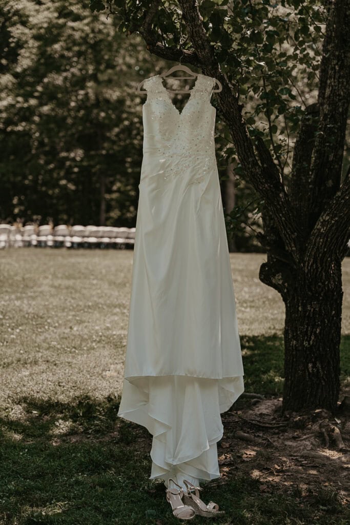 A wedding dress hangs from a tree outside.