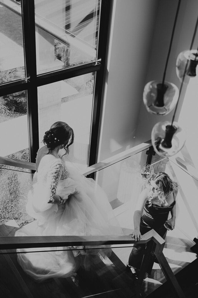 A black and white image of a bride walking down a staircase.