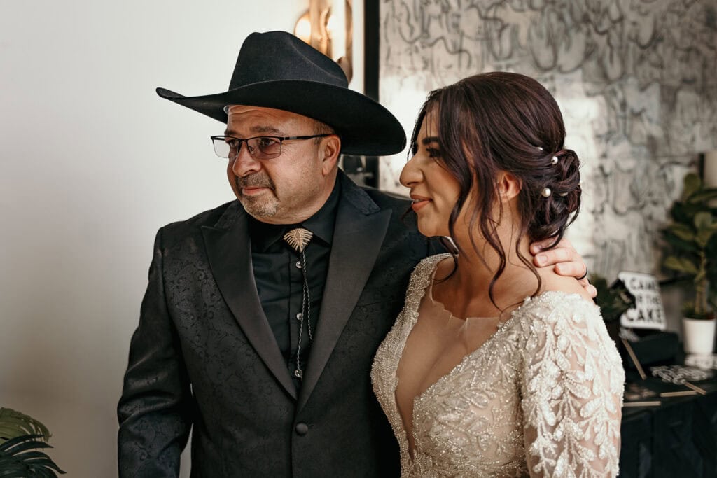 An emotional Dad has his arm around his daughter's shoulders on her wedding day.