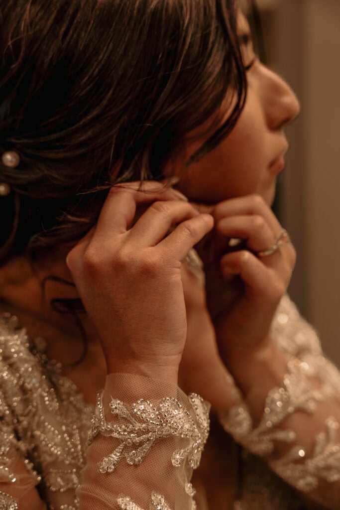 A bride puts her earrings in.