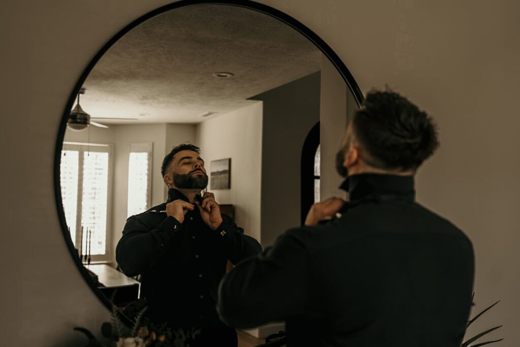 Kyle adjusts his bowtie in the mirror on his wedding day.