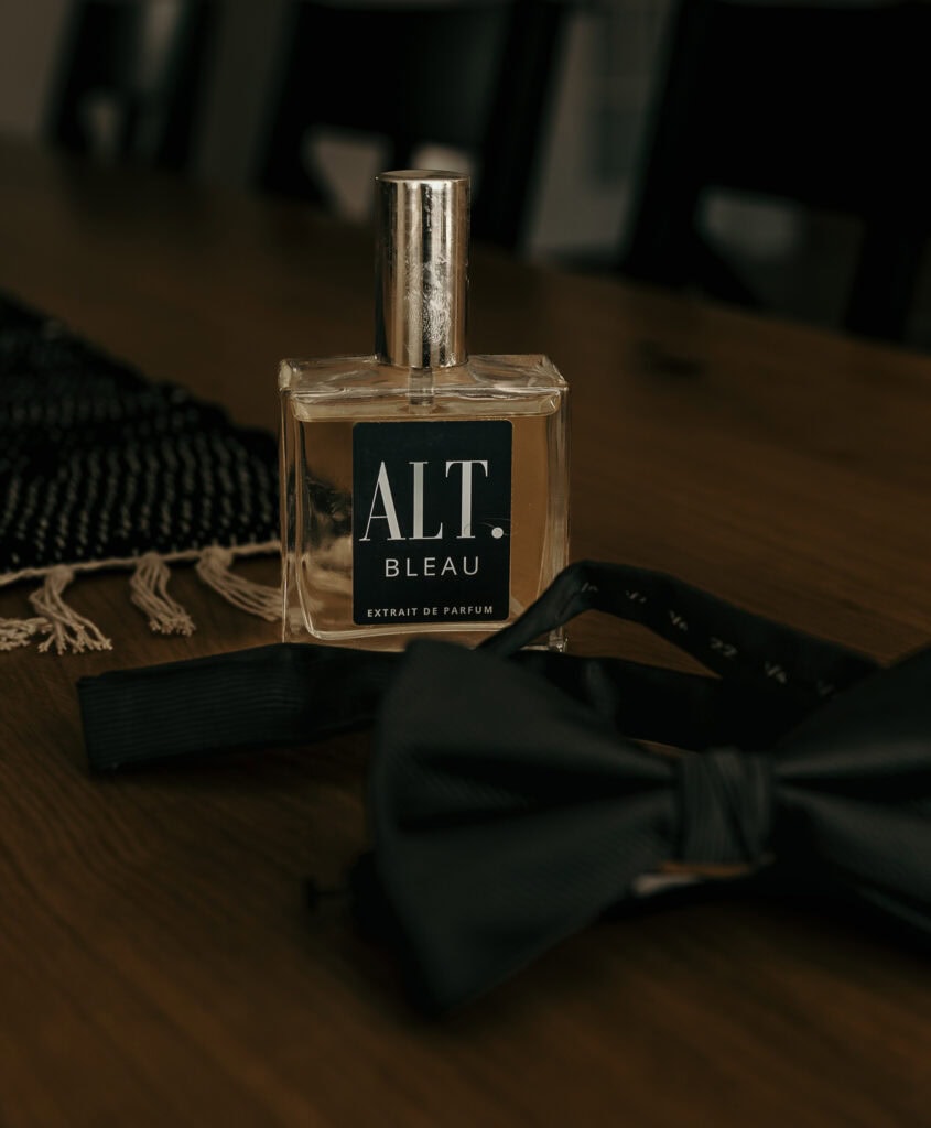 A groom's cologne and bowtie set on a table.