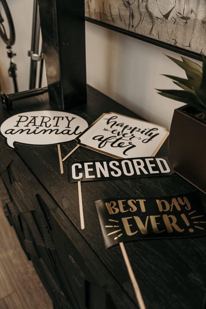 Signs for a photobooth set on a table at a wedding reception.