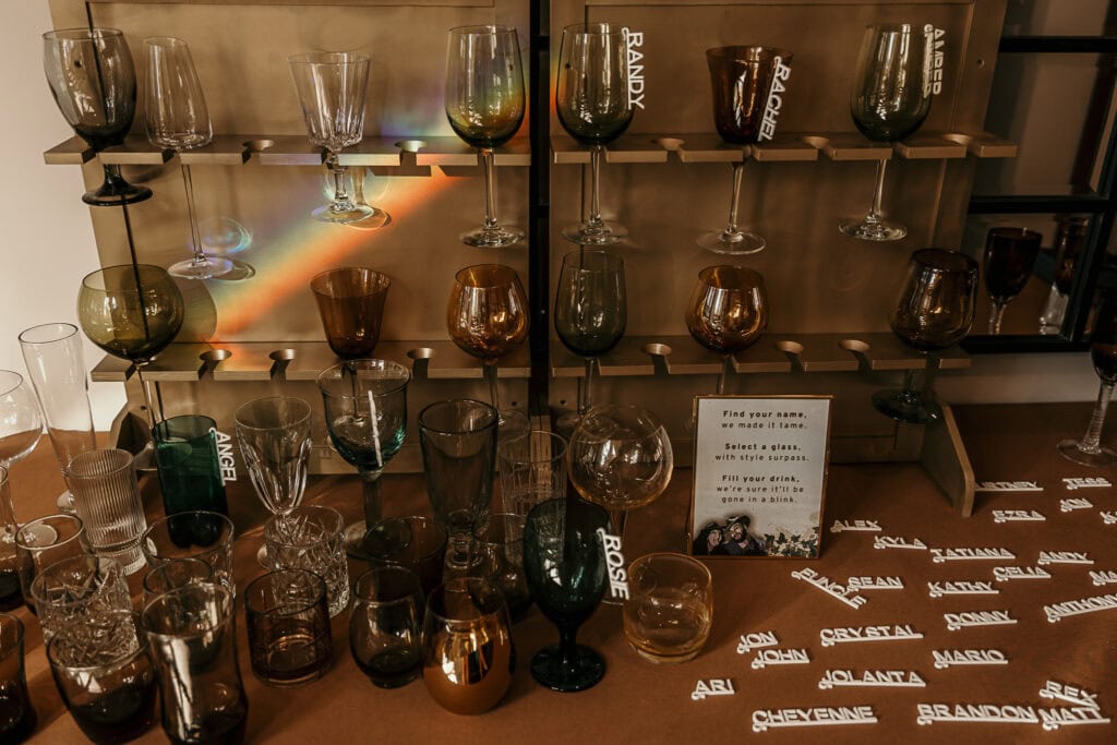 A prism shines on a table and shelf of colorful glasses at a wedding reception.