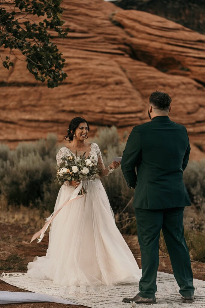 Bride laughs as the groom recites his vows during their wedding ceremony.