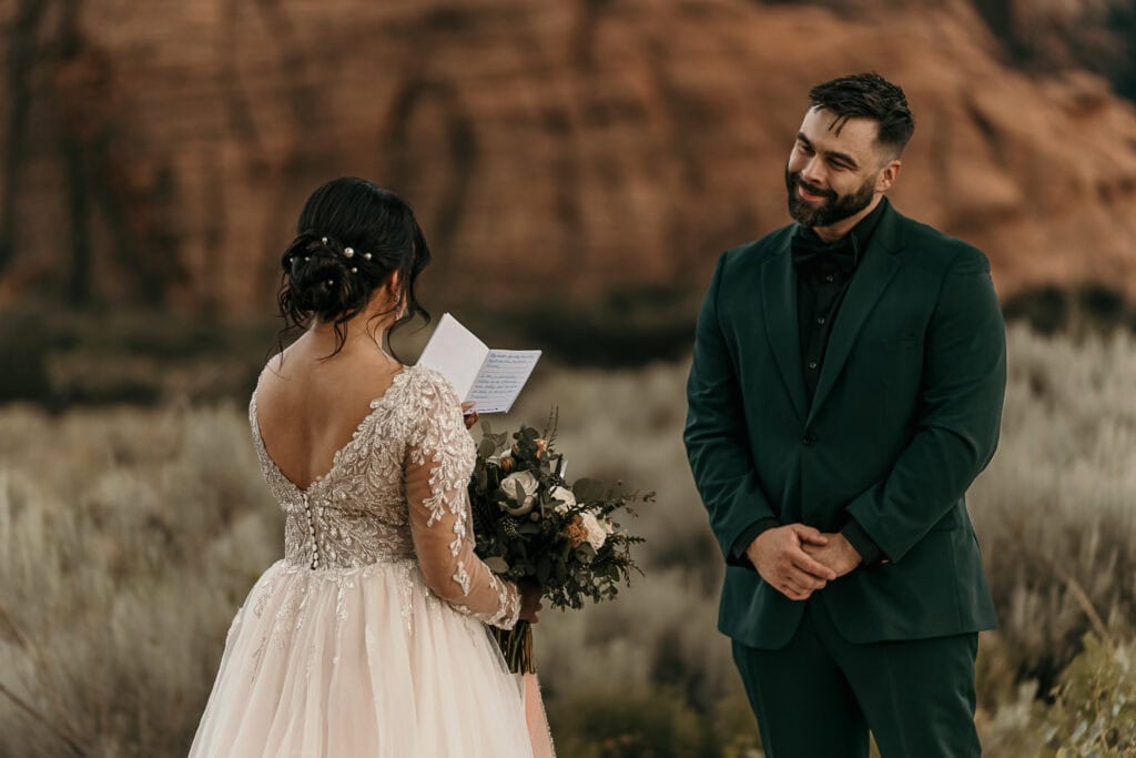 Kyle looks adoringly at Amaris as she reads her handwritten vows during their outdoor wedding.