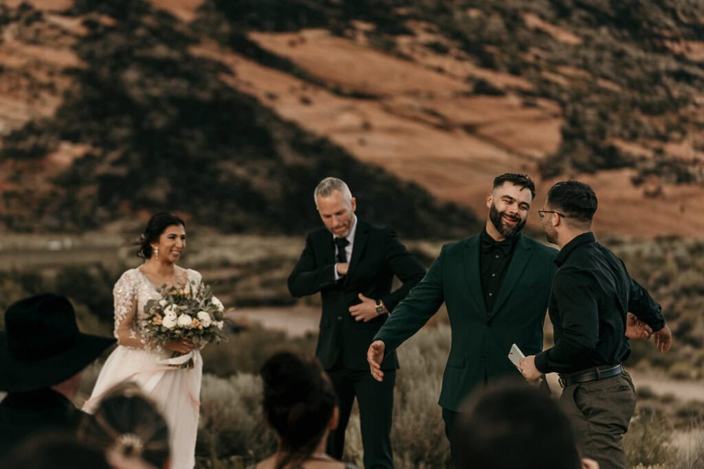 Groom greets his friend as he walks to the front of their outdoor wedding area to give a speech.