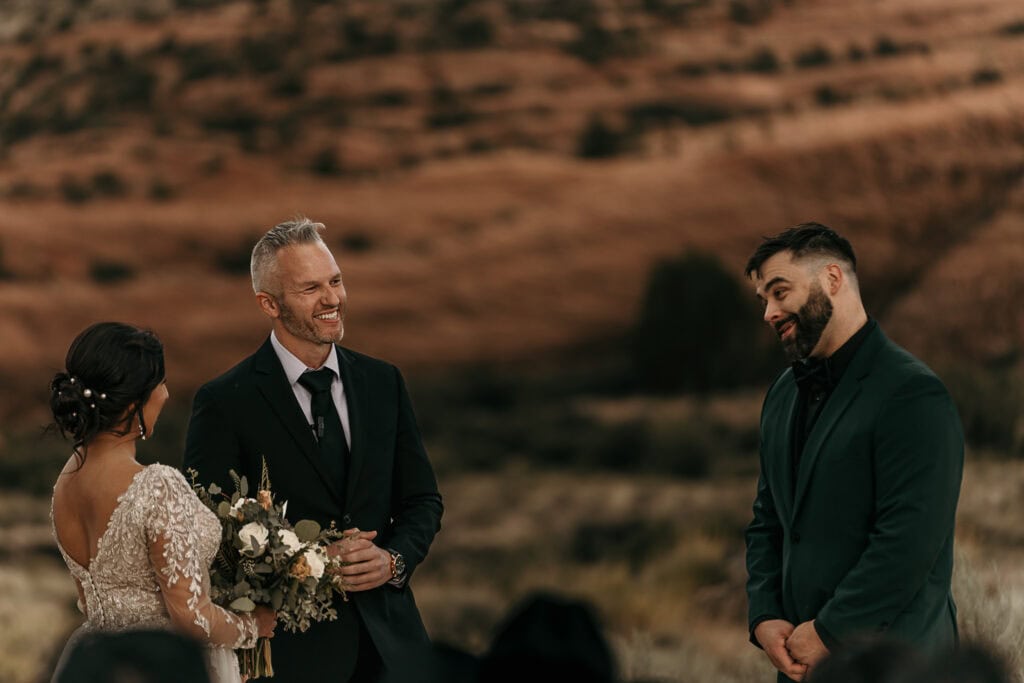 Groom tilts his head at something funny the officiant is saying.