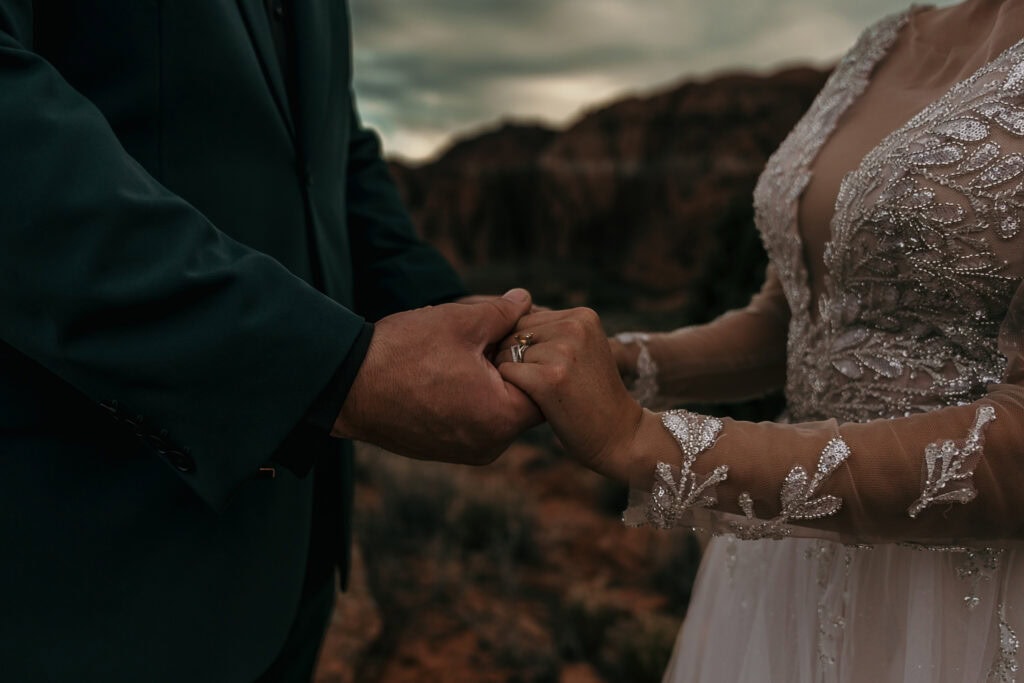 Bride and groom hold hands in front of red rocks in Snow Canyon State Park