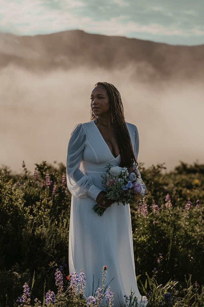 a dreamy bridal portrait in the wildflowers with smoky fog in the background