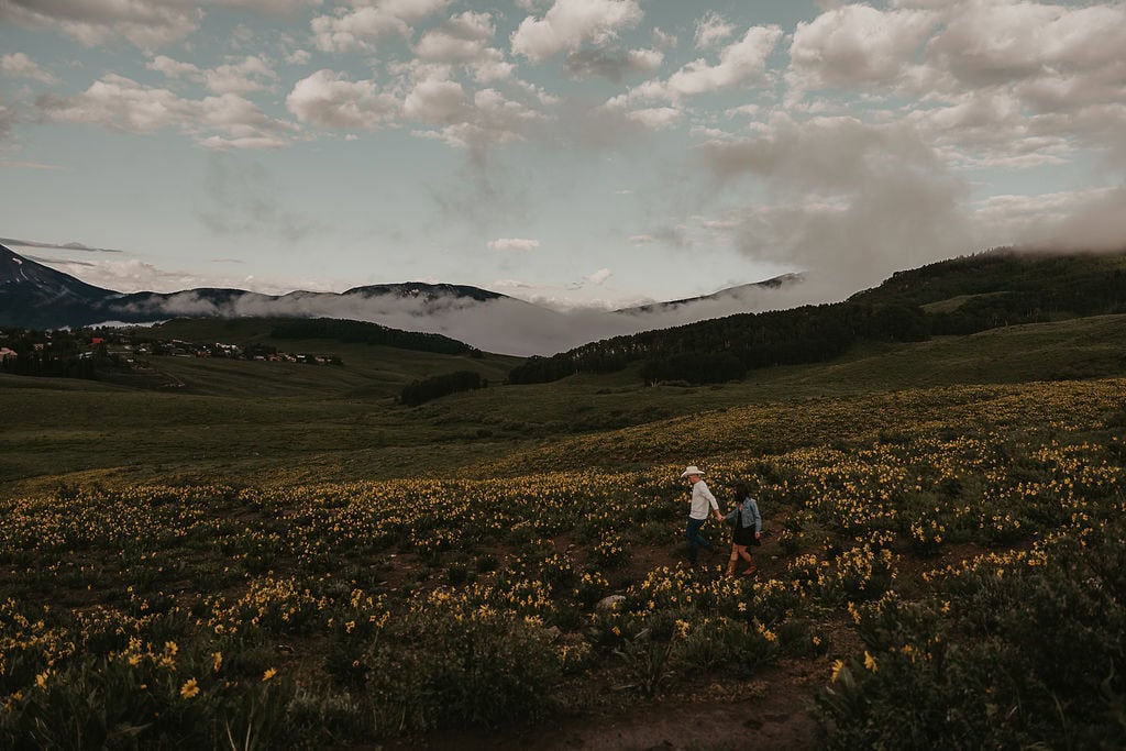 a couple roaming through a field of wildflowers in crested butte