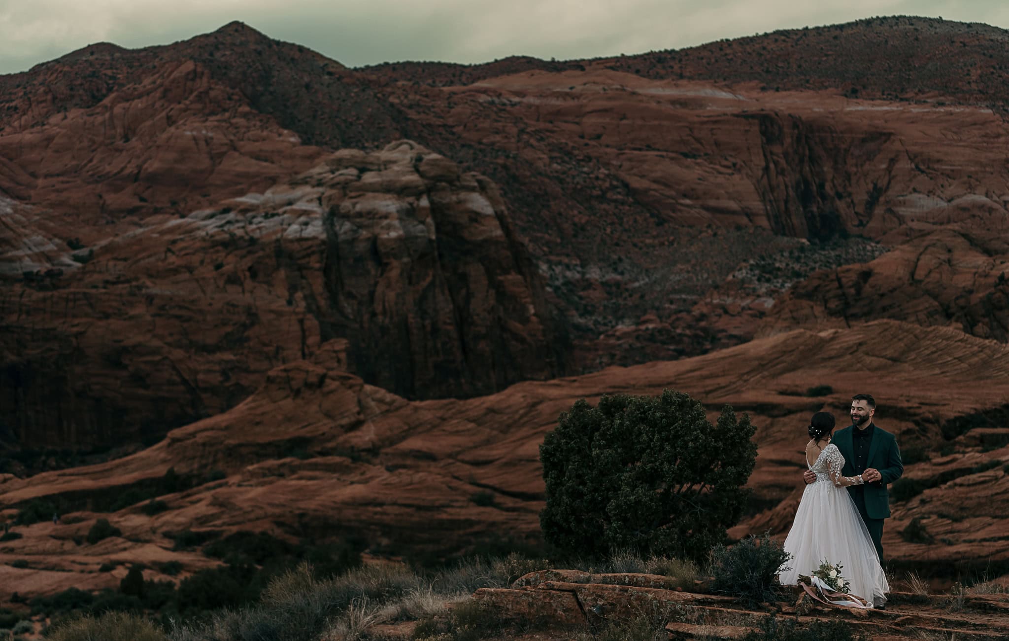 A couple dances in front of Utah's red rocks during their wedding.