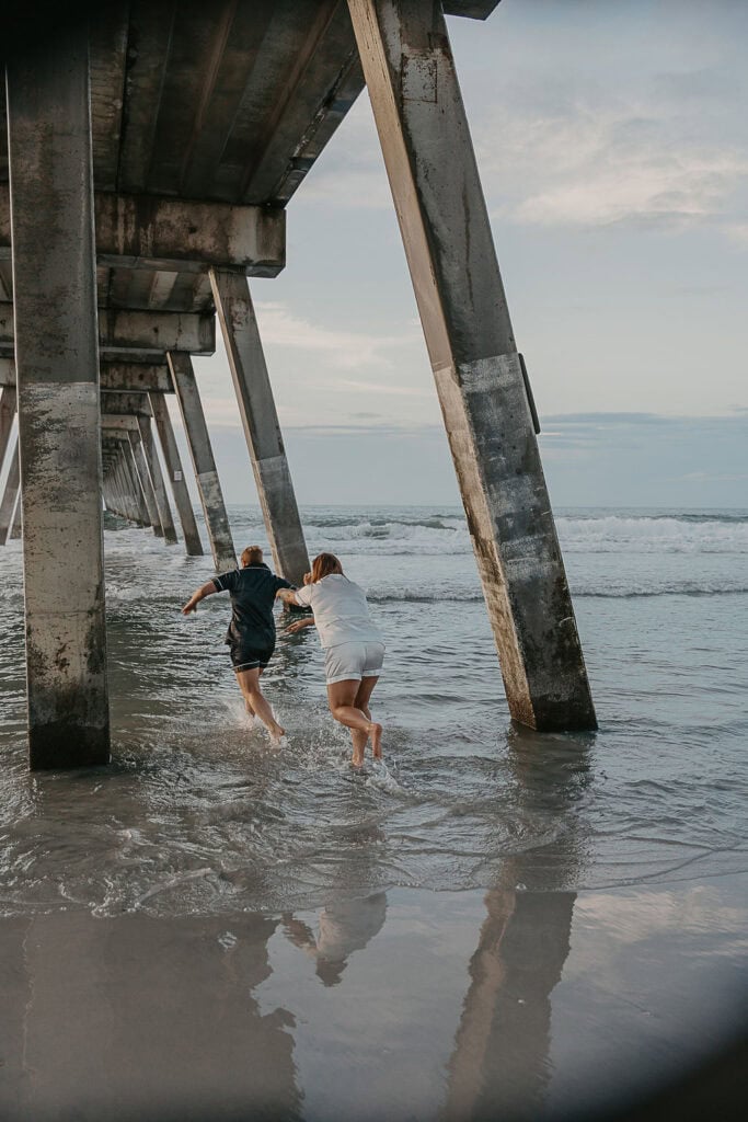 a playful couple playing with each other in the water at the beach in Wilmington NC