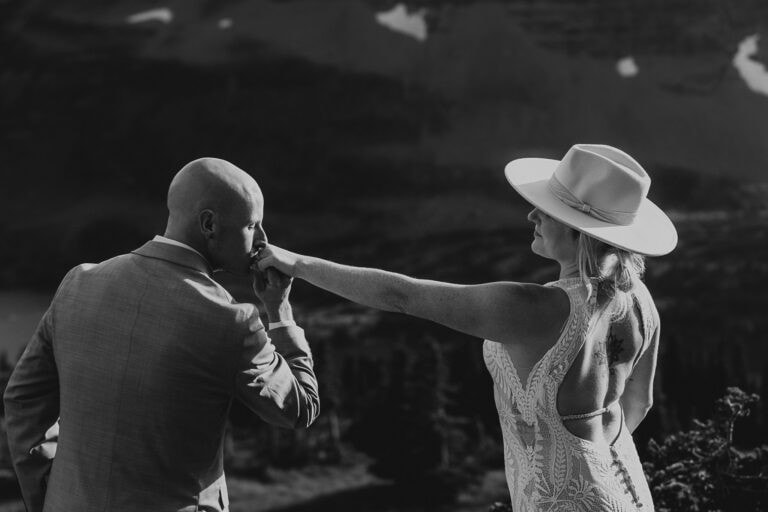 A black and white image of a groom kissing his bride's hand.