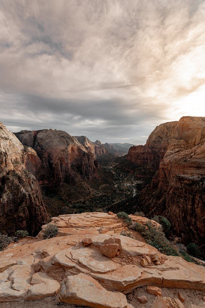 Capture of the dramatic Zion National Park cliffs during a tranquil sunset with a cloudy sky.