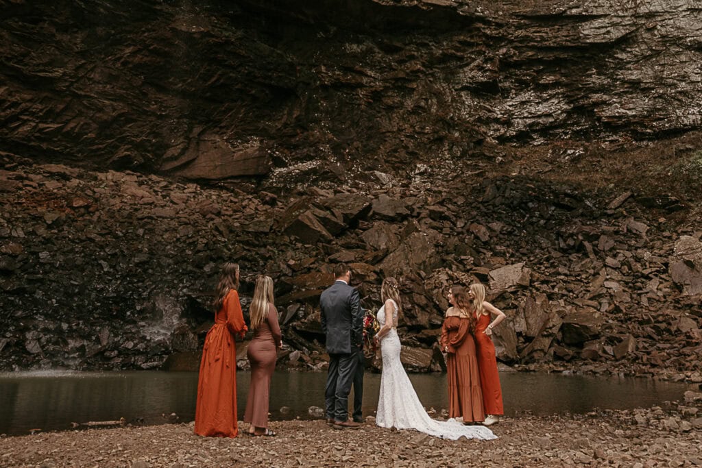 A wedding takes place at the base of Fall Creek Falls. The waterfall is barely flowing.